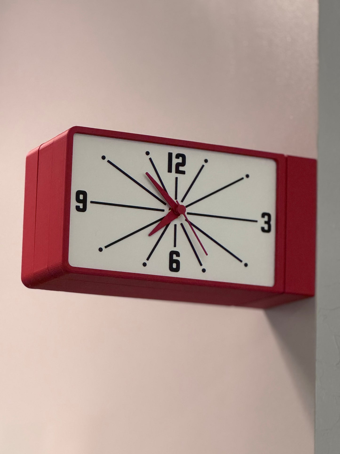 Red wall clock with white face on a light gray wall