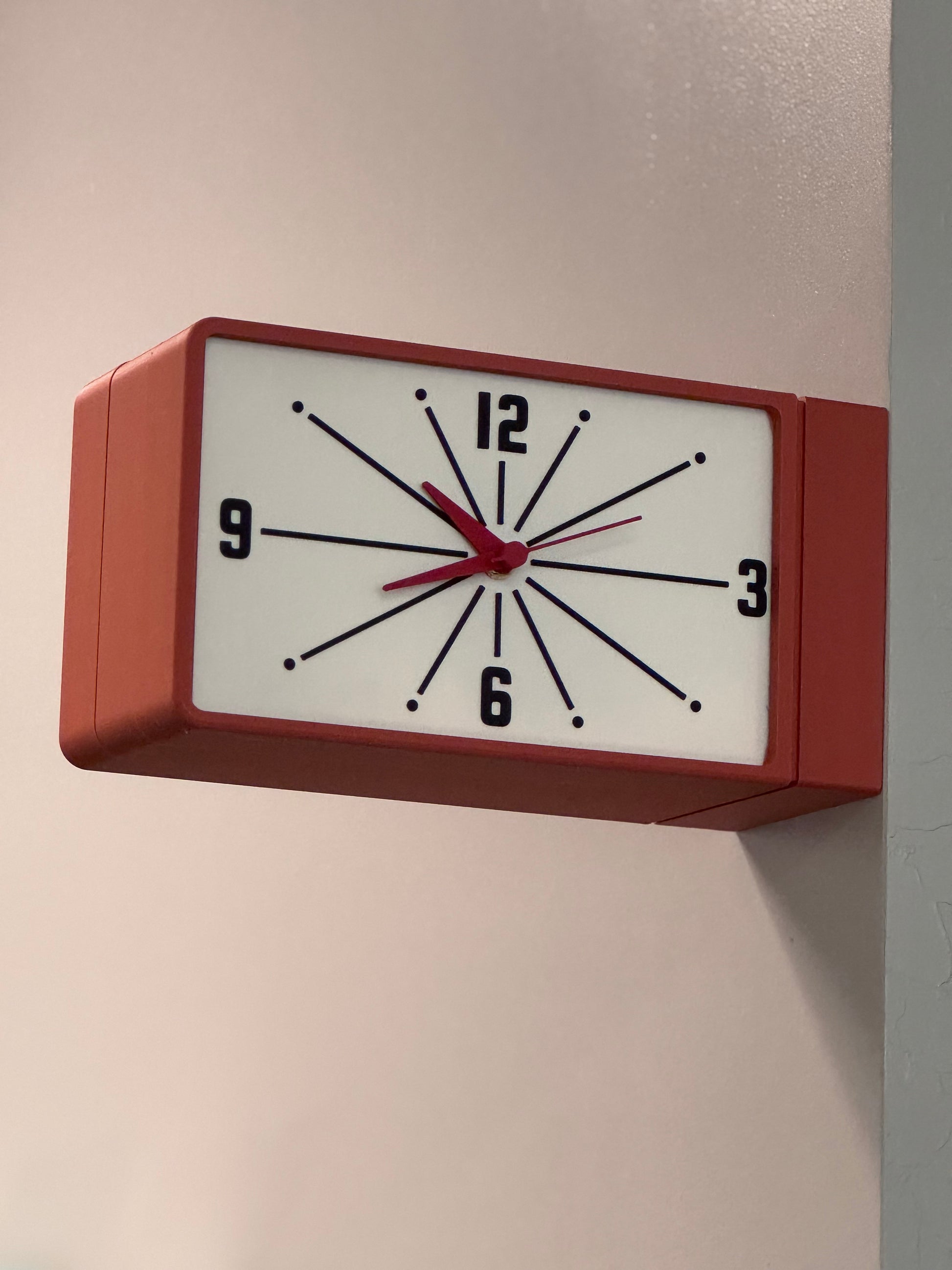 Rectangular clock with red frame on a plain wall